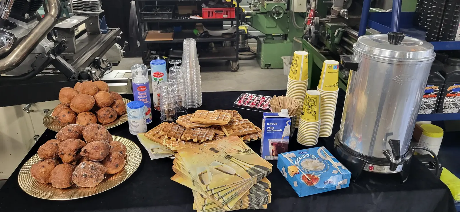 Oliebollen, wafels en koffie op een tafel voor de draaibank in de werkplaats