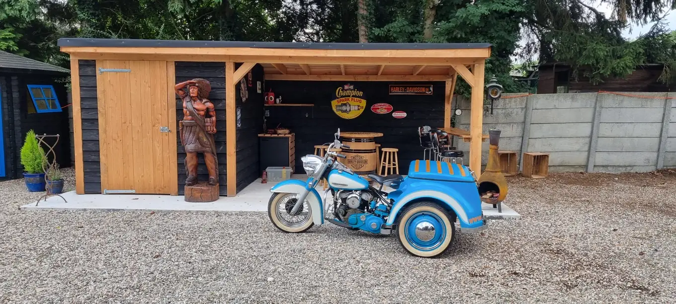 Blauwe trike met zijspanwiel voor een houten schuur