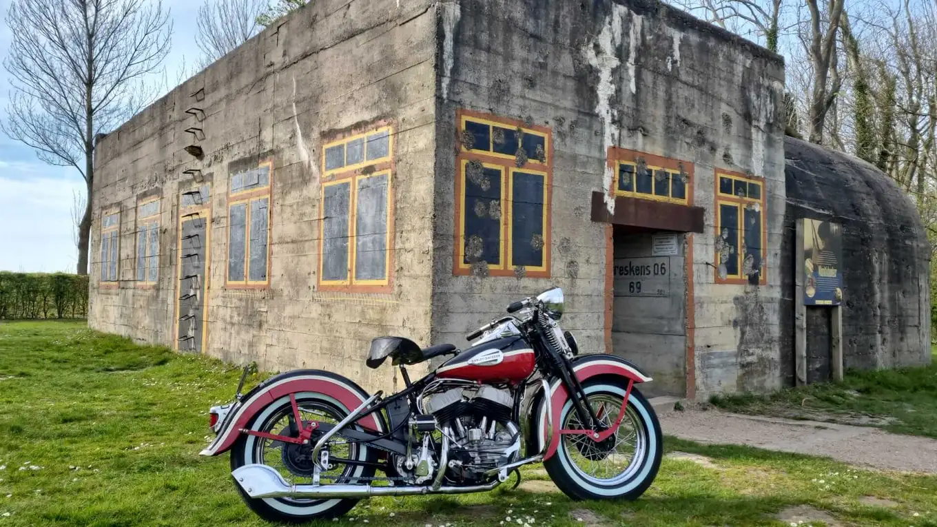 Gerestaureerde klassieke Harley-Davidson langs de kust, met de duinen op de achtergrond