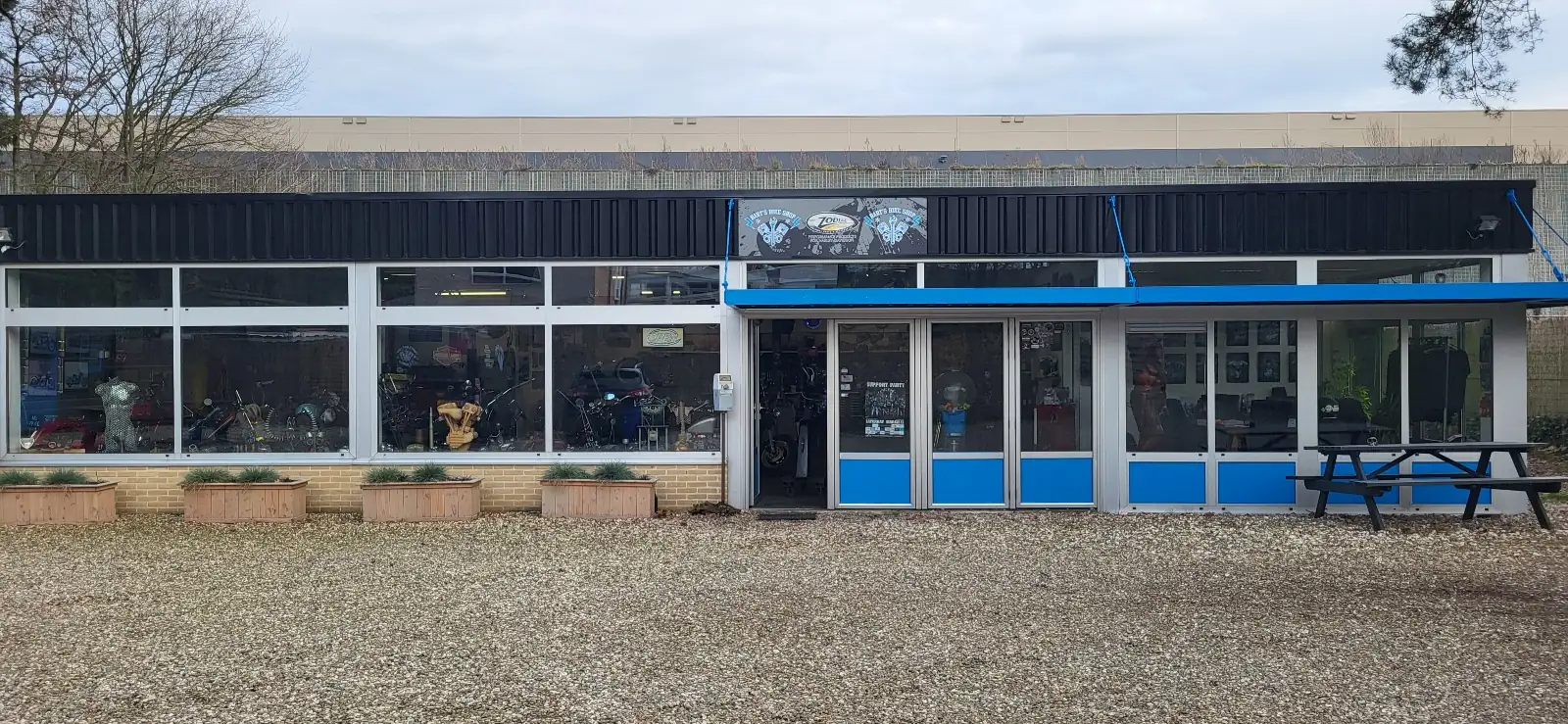 Het pand van Barts Bike Shop aan de Stationsweg in Herkenbosch, met blauwe kozijnen en motoren achter het raam